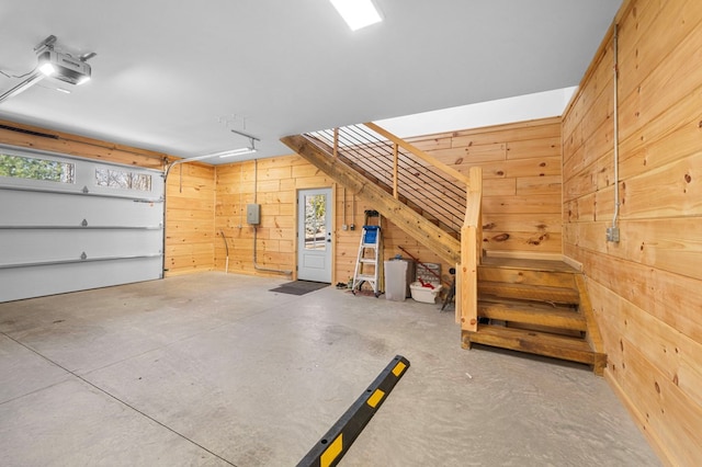 garage with a garage door opener, electric panel, and wood walls