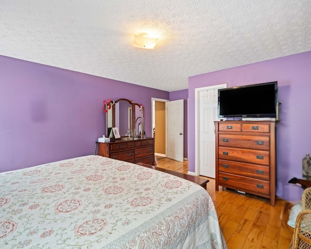 bedroom with a closet, a textured ceiling, and light wood-type flooring