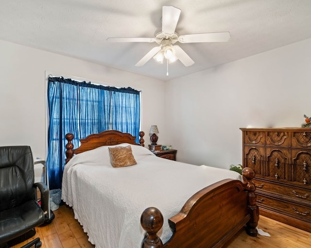 bedroom with ceiling fan, a textured ceiling, and light wood-type flooring