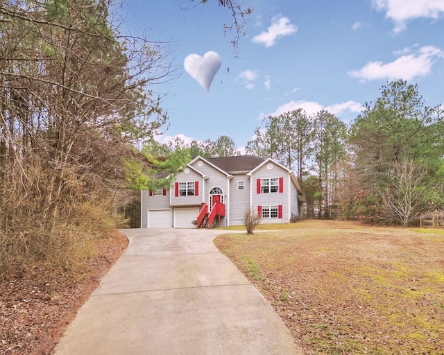 raised ranch featuring a garage and a front lawn