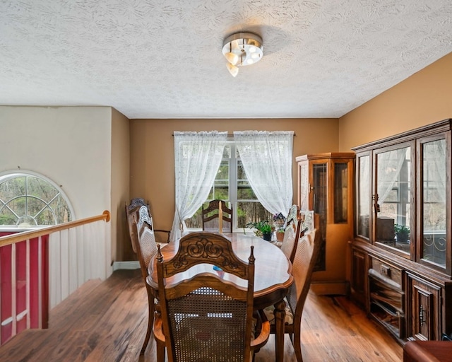 dining space with hardwood / wood-style flooring, a wealth of natural light, and a textured ceiling