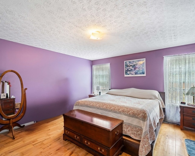 bedroom with a textured ceiling and light hardwood / wood-style flooring