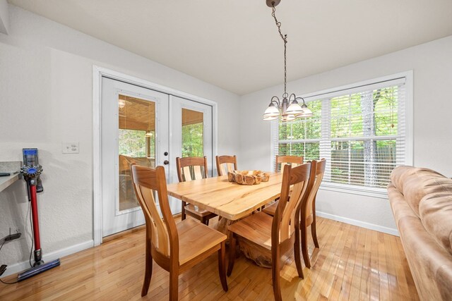 dining room featuring light wood-type flooring, a chandelier, and french doors