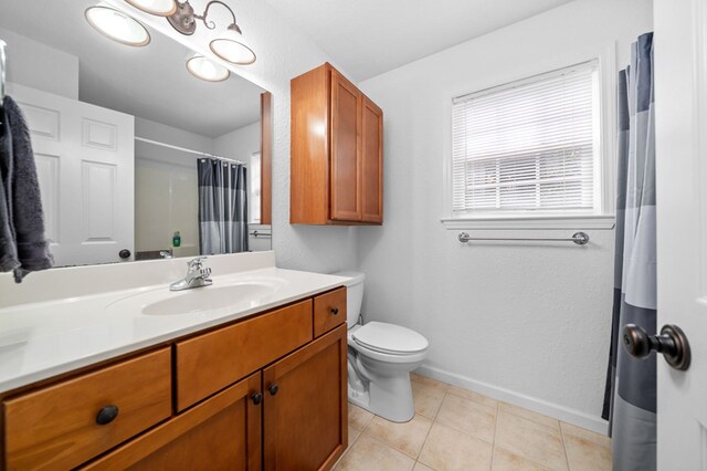 bathroom with a shower with shower curtain, tile patterned floors, vanity, and toilet