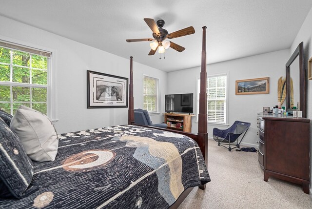 carpeted bedroom featuring multiple windows and ceiling fan