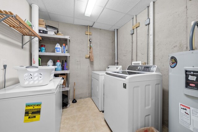 washroom with light tile patterned floors, washer and dryer, and electric water heater