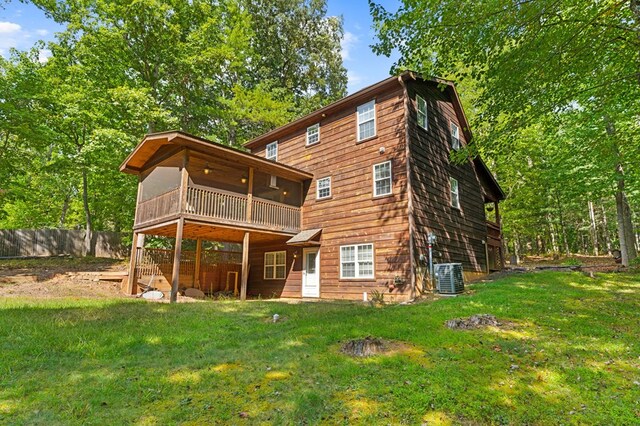 rear view of house featuring central AC unit, a balcony, and a lawn