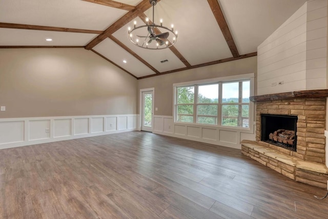 unfurnished living room featuring lofted ceiling with beams, a stone fireplace, dark hardwood / wood-style floors, and a chandelier