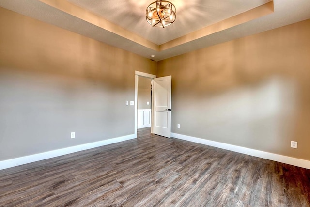 spare room featuring a tray ceiling and dark hardwood / wood-style floors