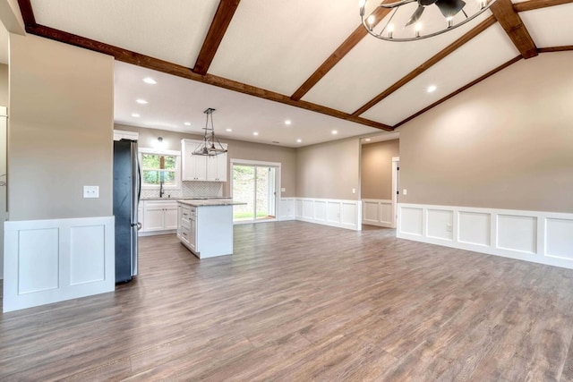 unfurnished living room featuring lofted ceiling with beams and wood-type flooring