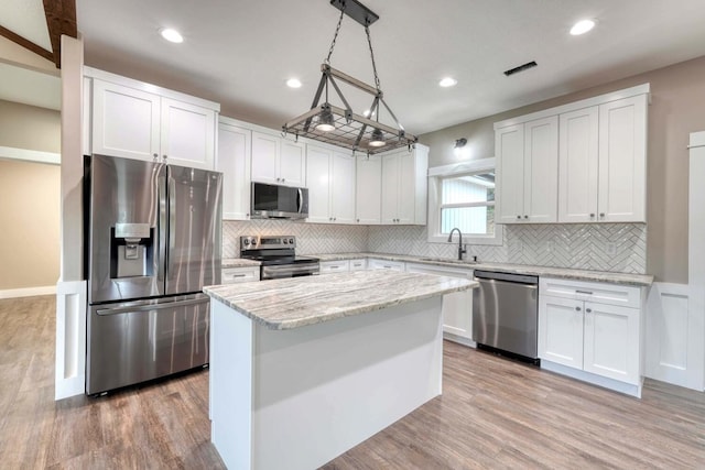 kitchen with a kitchen island, white cabinets, light wood-type flooring, and stainless steel appliances