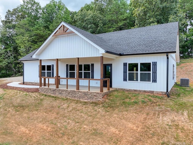 rear view of property with central AC unit, a lawn, and covered porch