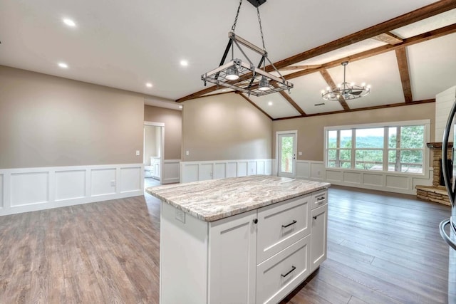 kitchen with vaulted ceiling with beams, white cabinetry, wood-type flooring, decorative light fixtures, and a center island