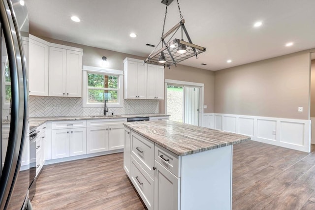 kitchen with sink, decorative light fixtures, a center island, and white cabinets