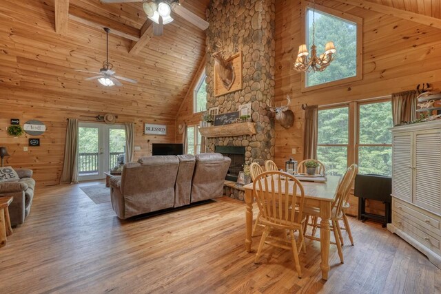 dining space with beam ceiling, wood walls, light hardwood / wood-style flooring, and high vaulted ceiling