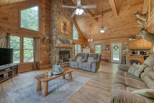 living room featuring beamed ceiling, a stone fireplace, light wood-type flooring, and high vaulted ceiling