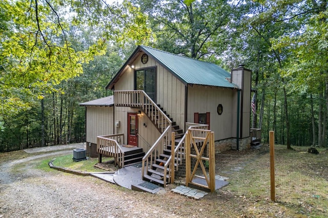 view of outbuilding featuring a forest view, stairway, and cooling unit