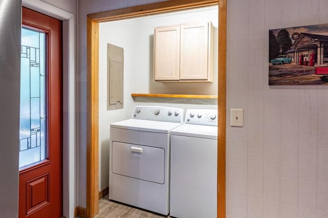 laundry area with light wood-type flooring, electric panel, cabinet space, and washer and dryer