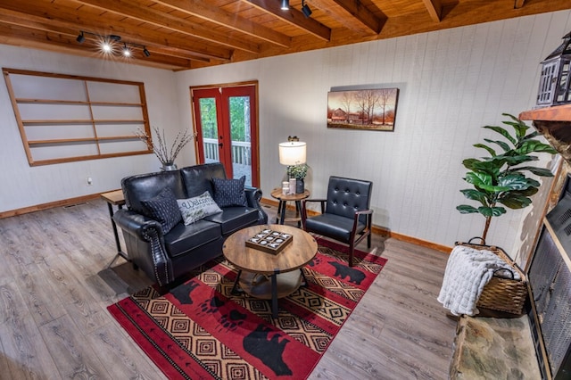 living area featuring beamed ceiling, wooden ceiling, wood finished floors, and baseboards