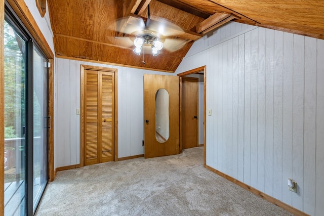 unfurnished bedroom with vaulted ceiling with beams, wooden ceiling, wooden walls, carpet flooring, and a closet