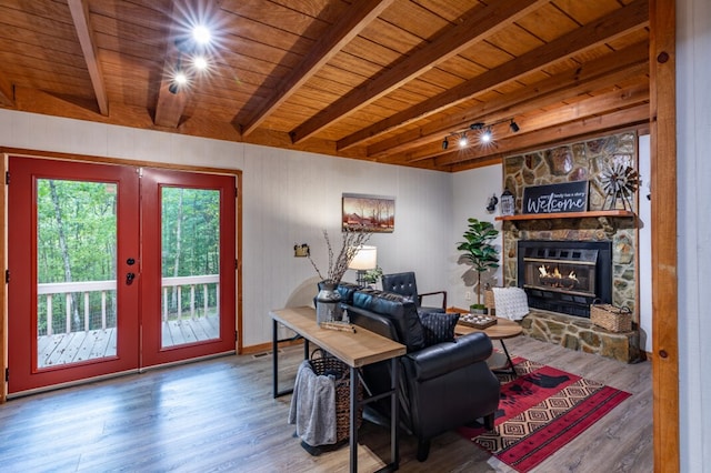 living room featuring wood ceiling, beamed ceiling, a stone fireplace, and wood finished floors