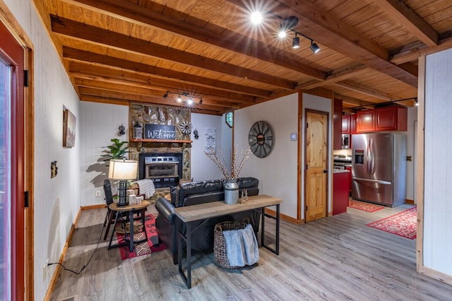 interior space featuring wood ceiling, a stone fireplace, beamed ceiling, and light wood-style flooring