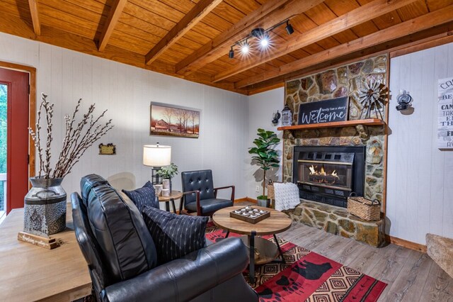 living room with beamed ceiling, wood-type flooring, a fireplace, and wood ceiling