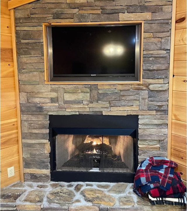 details featuring a stone fireplace and wooden walls