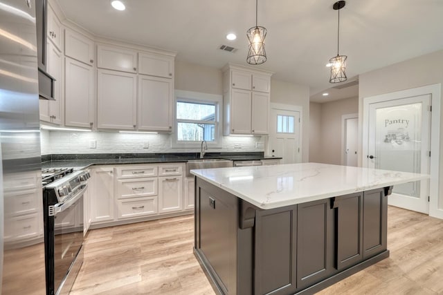 kitchen featuring white cabinets, stainless steel appliances, decorative light fixtures, and a kitchen island