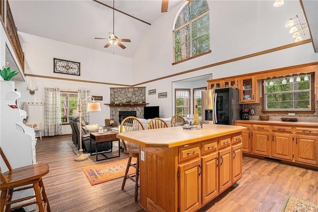 kitchen with a kitchen breakfast bar, fridge with ice dispenser, a fireplace, and light wood-style floors