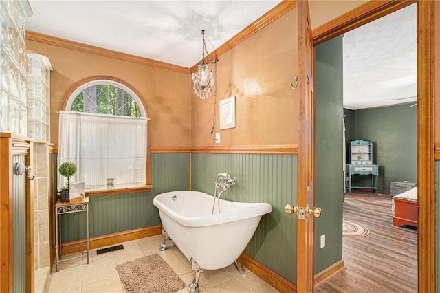 bathroom with tile patterned flooring, visible vents, crown molding, a wainscoted wall, and a freestanding tub