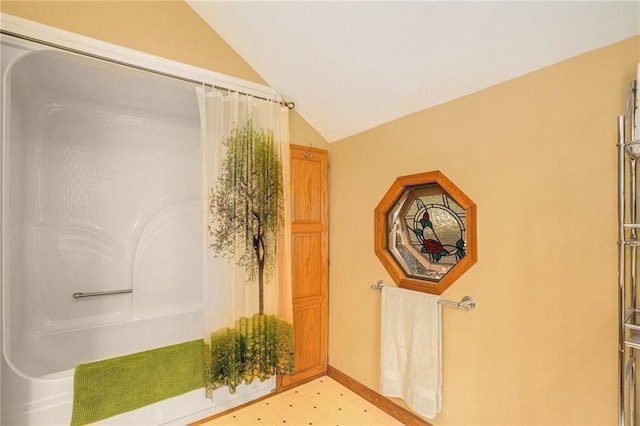 bathroom featuring tile patterned floors, baseboards, lofted ceiling, and a shower