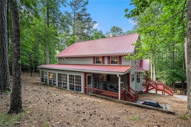 view of front of house with metal roof, stairs, and a sunroom