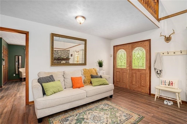 living area featuring a textured ceiling, baseboards, and wood finished floors