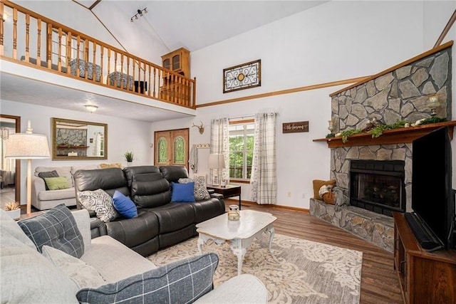 living room featuring baseboards, high vaulted ceiling, wood finished floors, and a fireplace