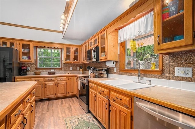 kitchen with decorative backsplash, stainless steel appliances, light countertops, and a sink