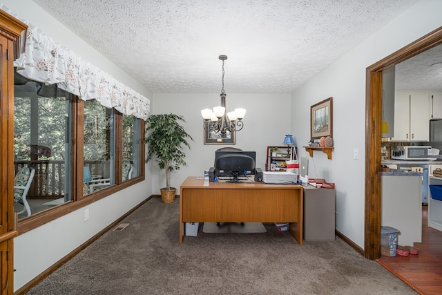 office space featuring an inviting chandelier, dark colored carpet, and a textured ceiling