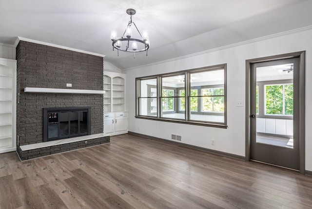 unfurnished living room featuring built in shelves, an inviting chandelier, hardwood / wood-style floors, lofted ceiling, and a fireplace