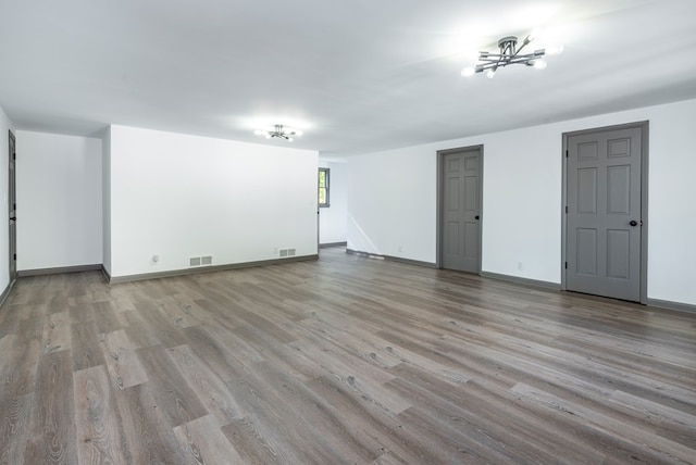 spare room featuring an inviting chandelier and light hardwood / wood-style flooring