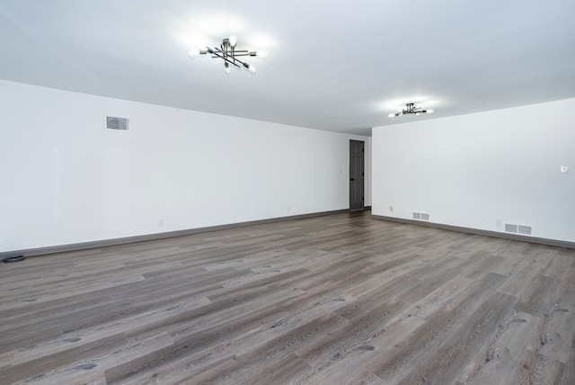 spare room with hardwood / wood-style flooring and an inviting chandelier