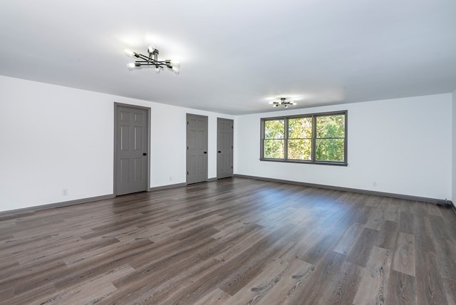 spare room with dark hardwood / wood-style flooring and an inviting chandelier