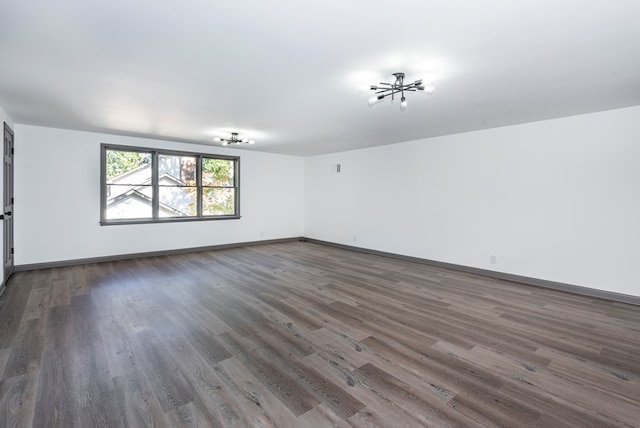 spare room with a chandelier and dark hardwood / wood-style floors