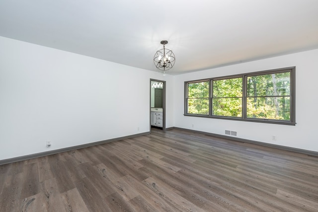 empty room featuring a chandelier and dark hardwood / wood-style flooring