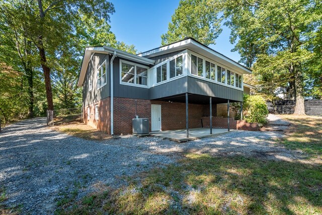 back of property with a sunroom, a patio, and central AC