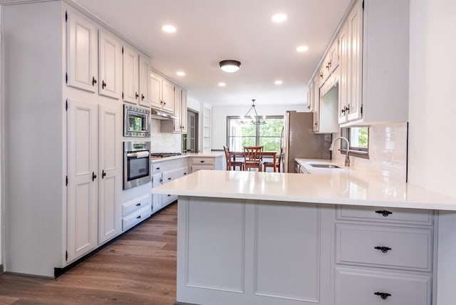 kitchen with white cabinets, sink, kitchen peninsula, and stainless steel appliances