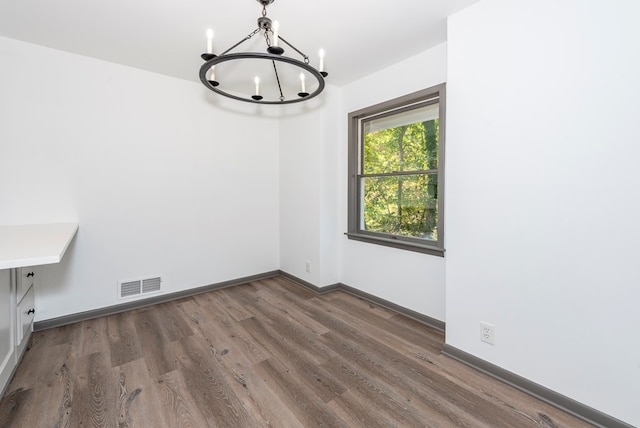 unfurnished dining area featuring dark hardwood / wood-style floors and an inviting chandelier