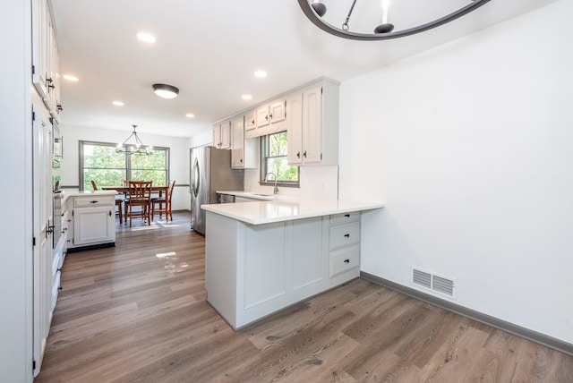 kitchen with white cabinets, dark hardwood / wood-style floors, kitchen peninsula, and sink