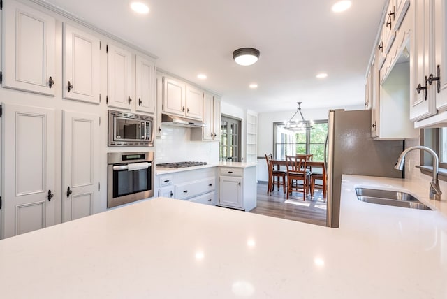 kitchen featuring decorative backsplash, stainless steel appliances, sink, decorative light fixtures, and white cabinetry