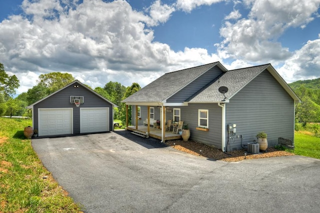 view of front of home featuring a porch, roof with shingles, a garage, central AC, and an outdoor structure
