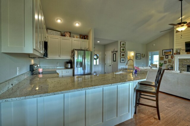 kitchen featuring a ceiling fan, appliances with stainless steel finishes, wood finished floors, a sink, and open floor plan